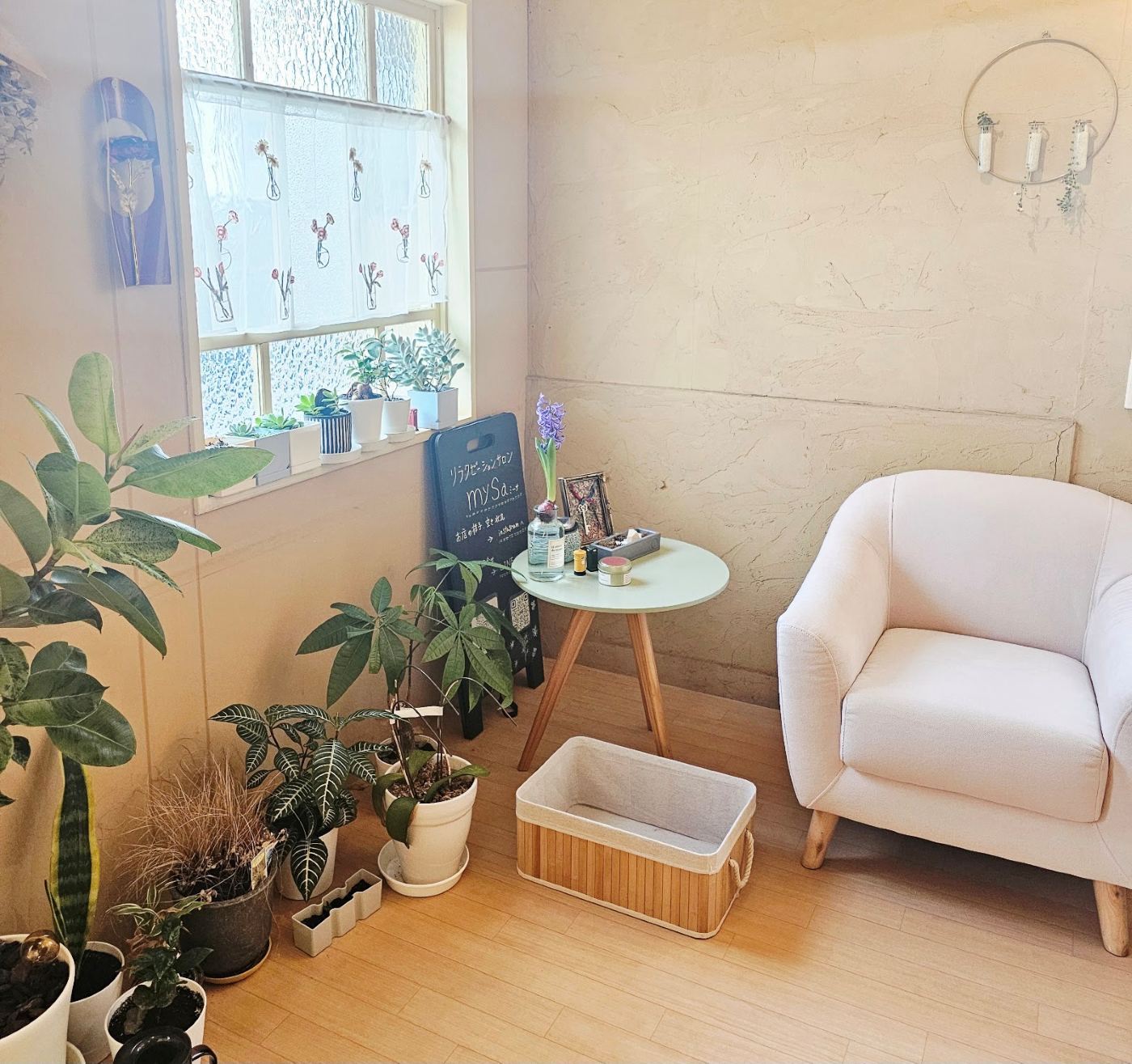 mysaの待合スペース。観葉植物と白いソファ、店名の書かれた看板